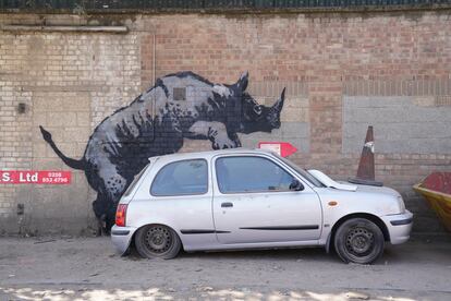 Bansky desvela su nueva obra de un rinoceronte escalando la superficie de un coche. Es la octava obra de la colección de animales, en la calle Westmoor en Charlton, Londres; este lunes.