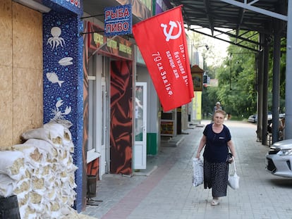 A woman walks past a shop decorated with a replica of a victory banner prior to local elections in Donetsk, the capital of Russian-controlled Donetsk region, eastern Ukraine, on Thursday, Sept. 7, 2023