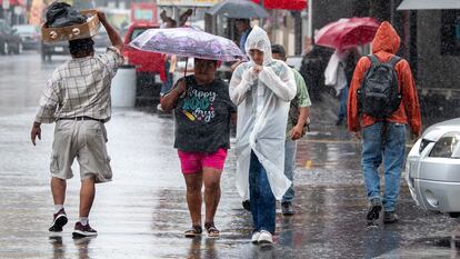 Personas caminan con paraguas e impermeables bajo la lluvia en Monterrey (Nuevo León), el 19 de junio.