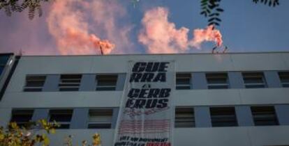 Algunas personas encienden botes de humo y despliegan una pancarta en el terrado del edificio de la sede de Haya Real State.