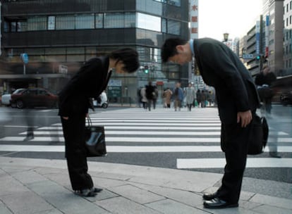 Dos ejecutivos japoneses se saludan de manera ceremonial en una calle de Tokio