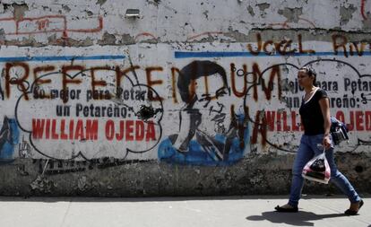 Una mujer pasa delante de un mural con la imagen de Hugo Ch&aacute;vez y una pintada que reza: Refer&eacute;ndum.