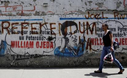 Una mujer pasa delante de un mural con la imagen de Hugo Chávez y una pintada que reza: Referéndum.