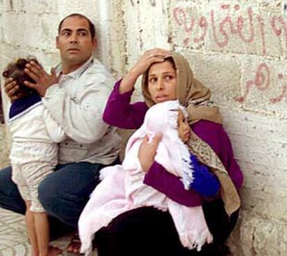 Una familia palestina se refugia junto a un muro durante el ataque de helicópteros israelíes en Gaza.