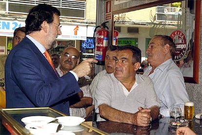 El líder del PP, Mariano Rajoy, charla con varios vecinos en un bar de la localidad madrileña de Coslada.