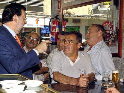 El líder del PP, Mariano Rajoy, charla con varios vecinos en un bar de la localidad madrileña de Coslada.
