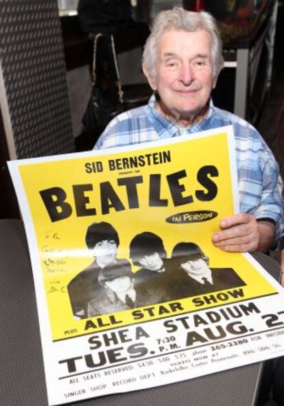 Sid Bernstein con el cartel del concierto de los Beatles en el Shea Stadium en 1965.