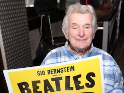 Sid Bernstein con el cartel del concierto de los Beatles en el Shea Stadium en 1965.