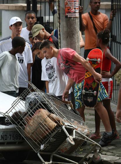 Un grupo de personas observa un cadáver metido en un carro de la compra, el pasado martes en la favela Morro dos Macacos.