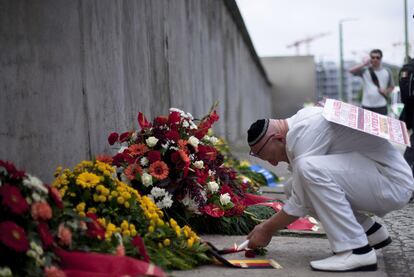 Un asistente enciende una vela en el lugar donde se ha conmemorado el 50 aniversario de la construcción del Muro, en la calle Bernauer de Berlín