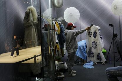 Una vendedora promociona prendas de XUNRUO durante una sesión de transmisión en directo, mientras una modelo en el escenario presenta creaciones de CHUSAN diseñadas por Guoqin Zhang, durante la Semana de la Moda de China, en Pekín.