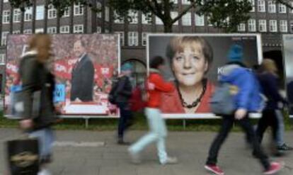 Jóvenes alemanes pasan por delante de carteles electorales del candidato socialista, Peer Steinbrueck, y de la canciller alemana, Angela Merkel.