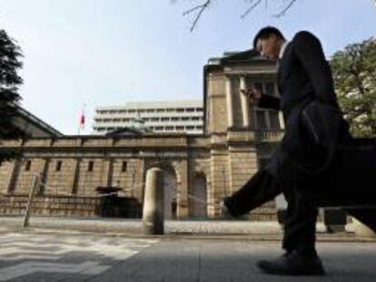 Un viandante mira su teléfono móvil mientras pasa delante de la sede del Banco de Japón (BOJ), Masaaki Shirakawa, en Tokio (Japón). EFE/Archivo