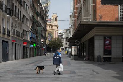 Un hombre pasea a su perro por la céntrica calle de Preciados durante el estado de alarma.