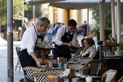 Varios camareros atienden una terraza de un bar de Sevilla.