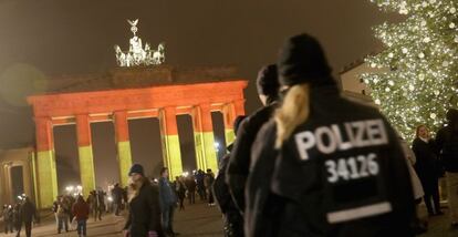 Policías alemanes patrullan en torno a la Puerta de Brandemburgo, en el centro de Berlín, iluminada con los colores de la bandera alemana.