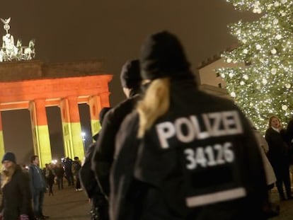 Policías alemanes patrullan en torno a la Puerta de Brandemburgo, en el centro de Berlín, iluminada con los colores de la bandera alemana.