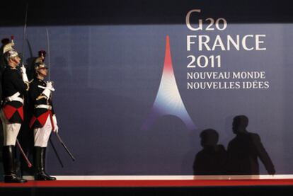 Las sombras de Angela Merkel y Nicolas Sarkozy se proyectan sobre el cartel de la cumbre del G-20, que ayer comenzó en la ciudad francesa de Cannes.