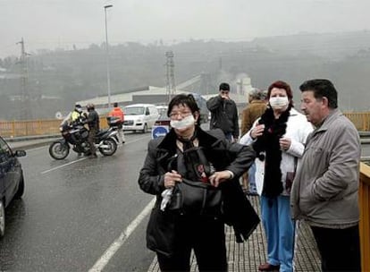 Personas con mascarilla en las inmediaciones del Pozo María Luisa de Sama de Langreo. Un incendio ha causado una densa nube de humo que ha disparado la alerta de Protección Civil en la zona.