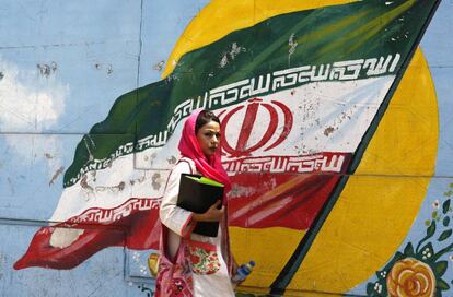 Una iraní pasa ante un mural con la bandera nacional en Teherán.