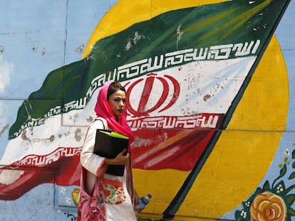 Una iraní pasa ante un mural con la bandera nacional en Teherán.