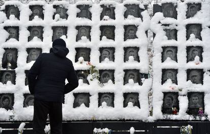 Un hombre mira los retratos de las personas que murieron durante 'Maidan', una ola de manifestaciones y disturbios civiles en Ucrania entre 2013-2014, cubiertos de nieve en el 'Heavenly Hundred Memorial', tras una intensa nevada en la capital ucraniana de Kiev.