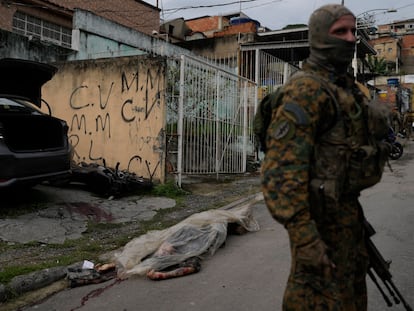 Un miembro de las fuerzas especiales de la Policía Militar de Río de Janeiro, junto al cadáver de un hombre muerto durante una operación policial en una favela el pasado febrero.