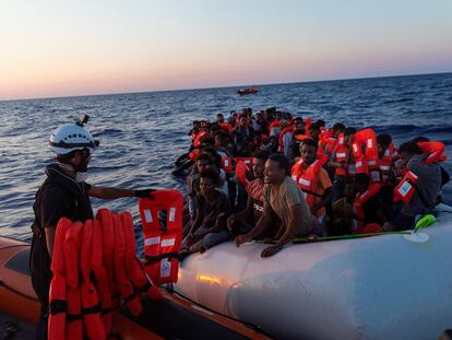 Un miembro del equipo de rescate del Sea-Watch 3 reparte chalecos salvavidas a los migrantes rescatados de un bote hinchable este sábado en el Mediterráneo Central.