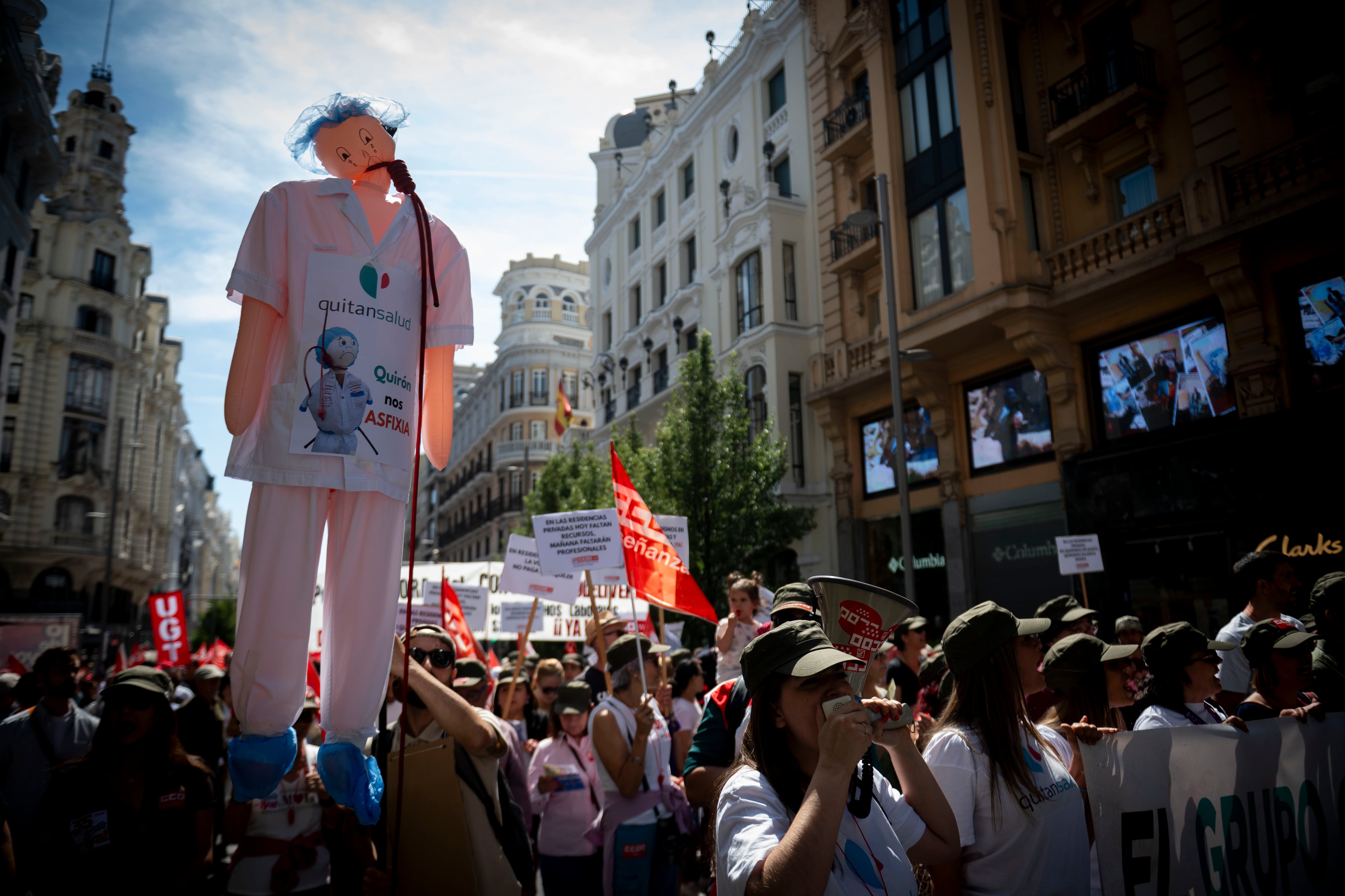Manifestantes exhiben un muñeco crítico con la gestión del grupo Quirón durante la marcha en Madrid.