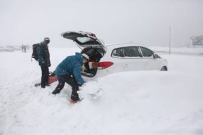 Two people dig their car out from the snow in Navacerrada, Madrid.