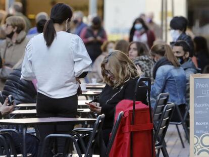 Un camarero atiende las mesas de una cafeteria del barrio de Sants de Barcelona hoy.