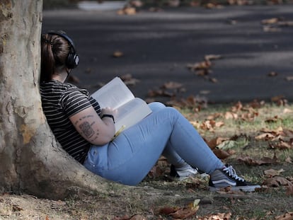 Una mujer lee un libro en un parque en Bilbao.