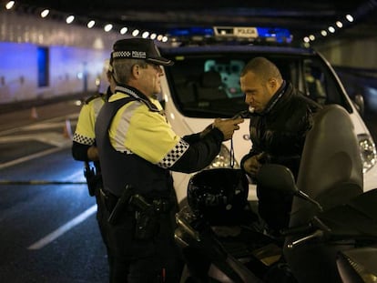 Un agente de la Guardia Urbana de Barcelona hace la prueba de alcoholemia a un motorista.