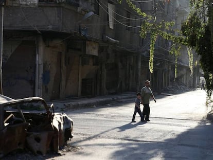 Un hombre y un ni&ntilde;o caminan por la zona rebelde de Ain Tarma, en Ghuta, al este de Damasco.