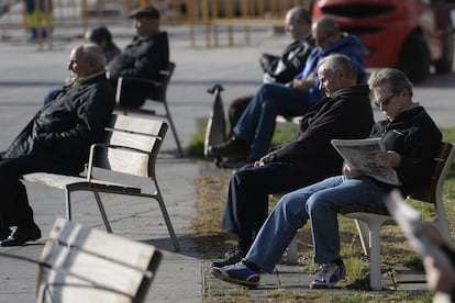 Un grupo de pensionistas toman el sol en un banco de una calle de Barcelona.