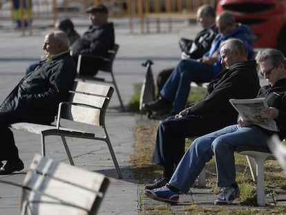 Un grupo de pensionistas toman el sol en un banco de una calle de Barcelona.