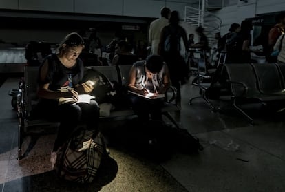 Un grupo de mujeres, este viernes, llenando su forma de reclamo de equipaje en la oscuridad del aeropuerto Simón Bolívar de Caracas.