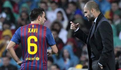 Xavi recibe instrucciones de Guardiola durante un partido