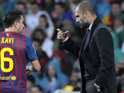 Xavi recibe instrucciones de Guardiola durante un partido