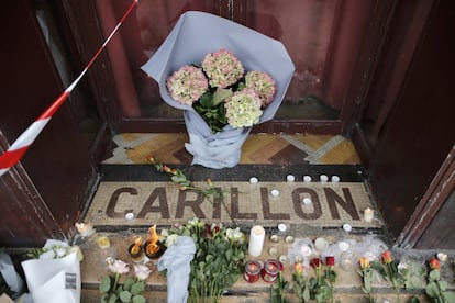 Ofrendas florales y velas de pie en la entr.ada al restaurante Carillon, en París.