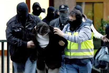 Varios agentes trasladan detenido a uno de los presuntos atracadores capturados en Bilbao.