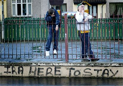 Dos niños norirlandeses, junto a un pintanda en la que se lee <i>El IRA está aquí para quedarse</i>, en Londonderry.