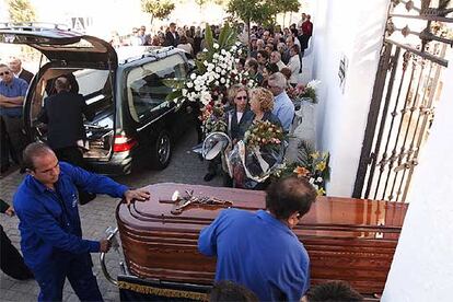 Empleados de la funeraria trasladan el fretro de una de las personas asesinadas en Ayamonte.