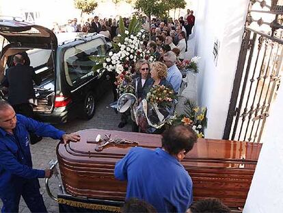 Empleados de la funeraria trasladan el féretro de una de las personas asesinadas en Ayamonte.