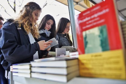 Tres jóvenes en una caseta de la Fira del Llibre de Valencia.