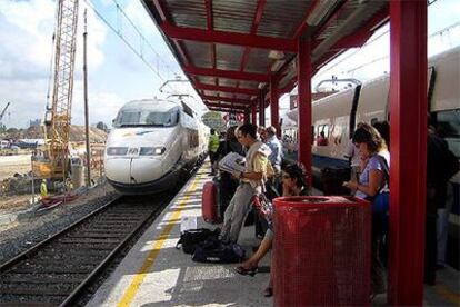 Los pasajeros atrapados por la avería en la estación de El Prat. A la izquierda, el tren que los recogió; a la derecha, el averiado.