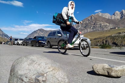 Dos hombres en bicicleta y una caravana de coches cruzaban la frontera de Rusia con Georgia para evitar la movilización, en septiembre.