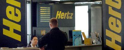 Un hombre permanece en un mostrador del servicio de alquiler de vehículos Hertz.