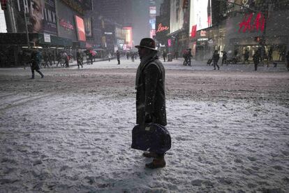Un hombre permanece bajo la nieve en Times Square en Nueva York.