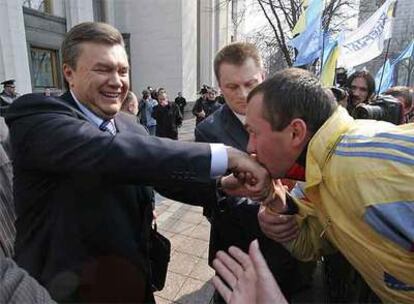 Un hombre besa la mano del primer ministro ucranio, Víktor Yanukóvich, a las puertas del Parlamento ayer en Kiev.